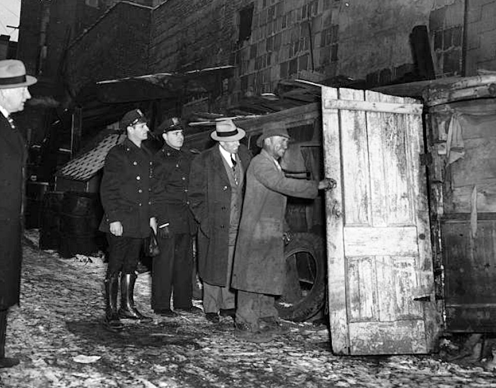 Broome Street
1935: The owner of a shack made from a scrapped bus opens his door for Director Brady of the Newark Department of Public Affairs and Health Officials in Broome Street, Newark. 

Photo by Hulton Archive
